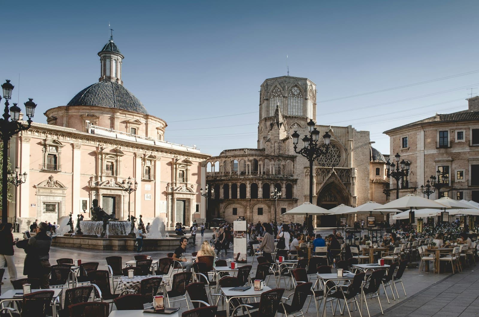 Terrazas con sombrillas y mesas llenas de gente en la plaza de la Virgen de Valencia, junto a la basílica y la catedral