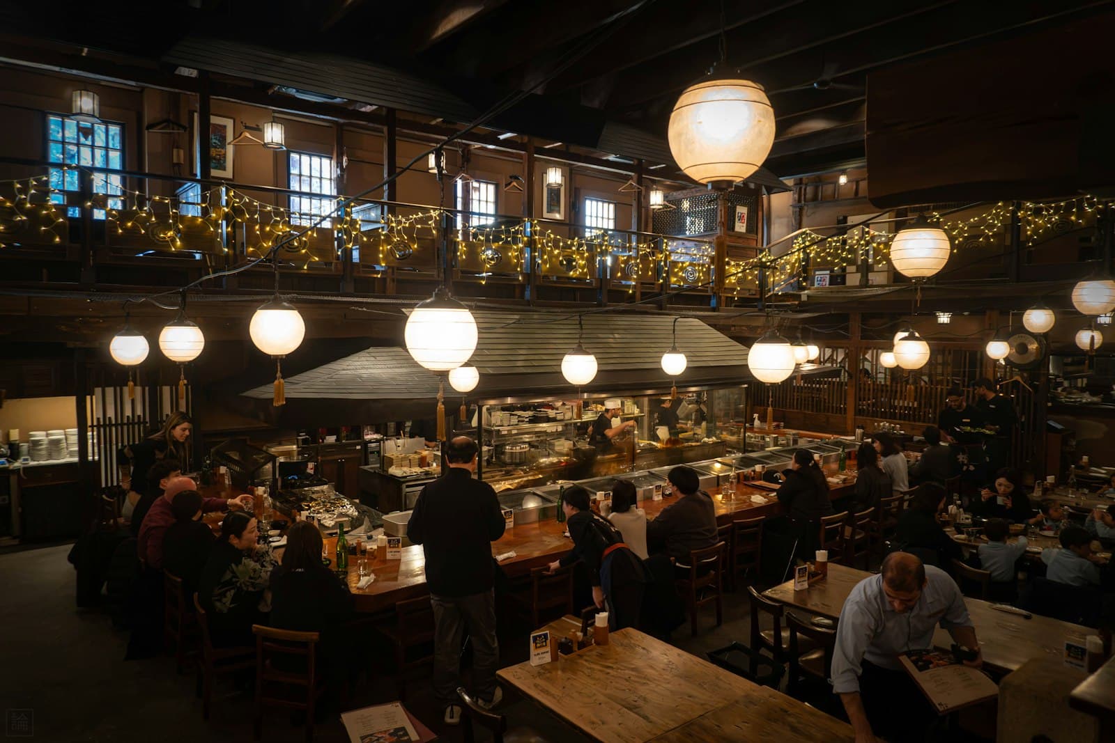 Comedor de restaurante lleno de clientes por la noche con lámparas de papel