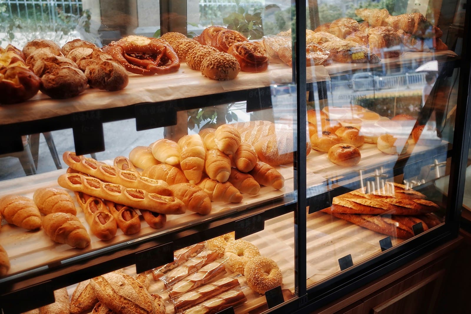 Vitrina de una panadería con barras, bollos y piezas de bollería en baldas de madera