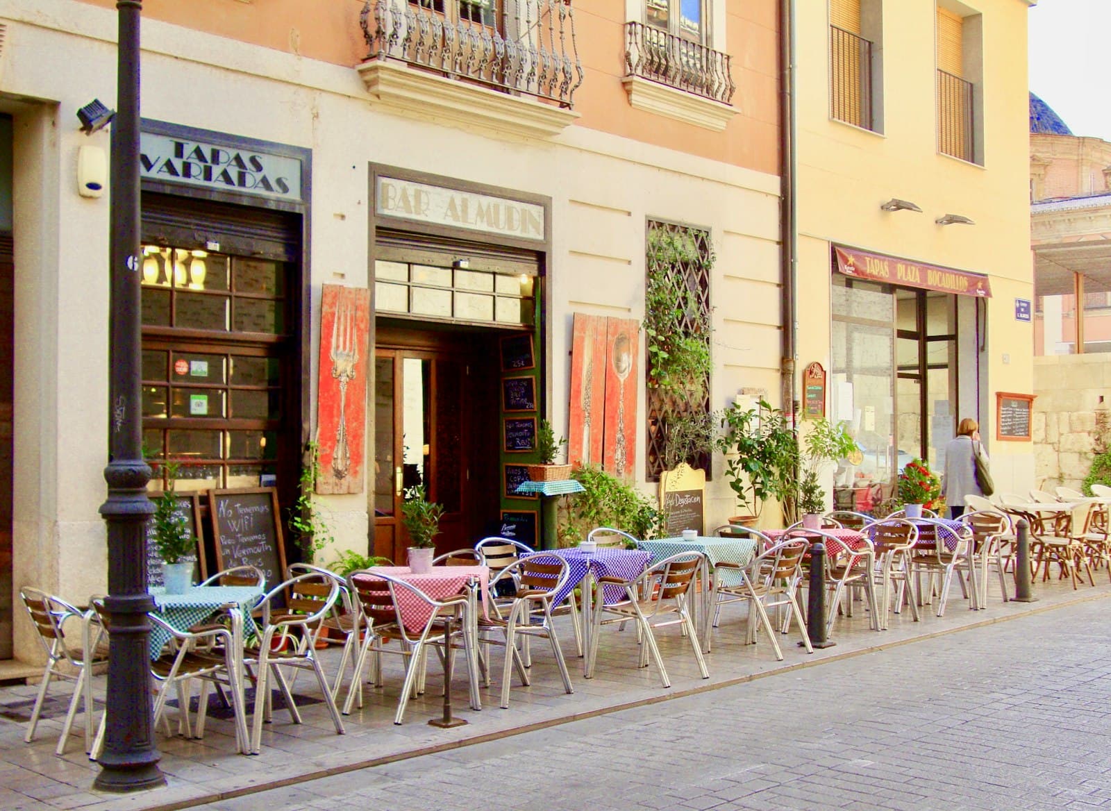 Terraza de un bar de tapas con mesas de manteles de cuadros en una calle peatonal