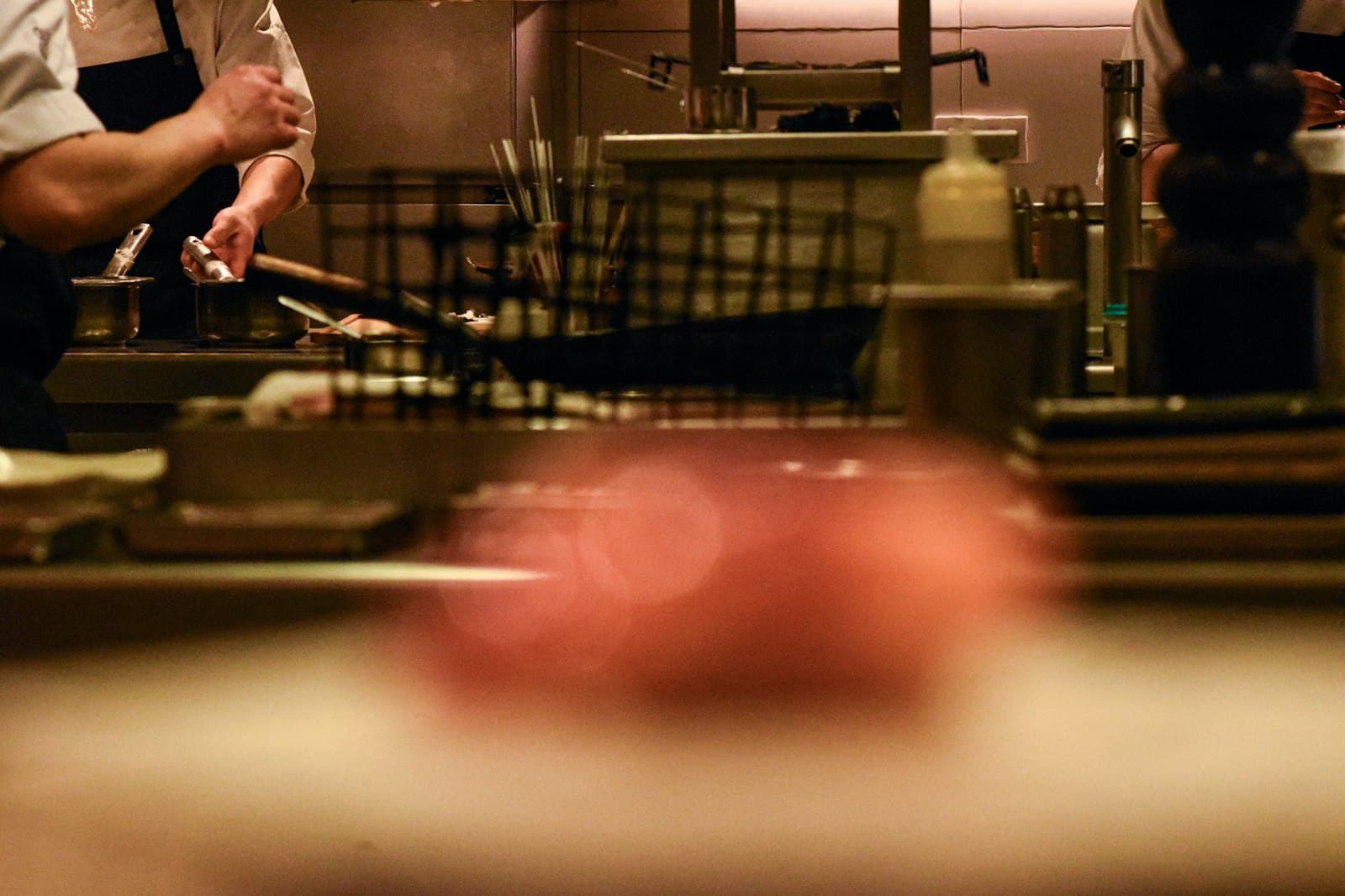 Cocineros trabajando en el pase de la cocina de un restaurante durante el servicio de noche