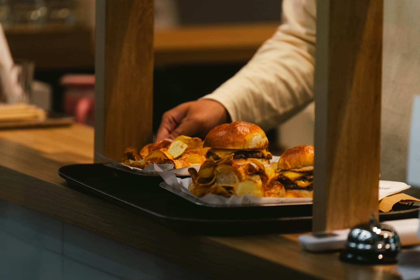 Bandeja con hamburguesas y patatas fritas sobre el mostrador de recogida de un restaurante