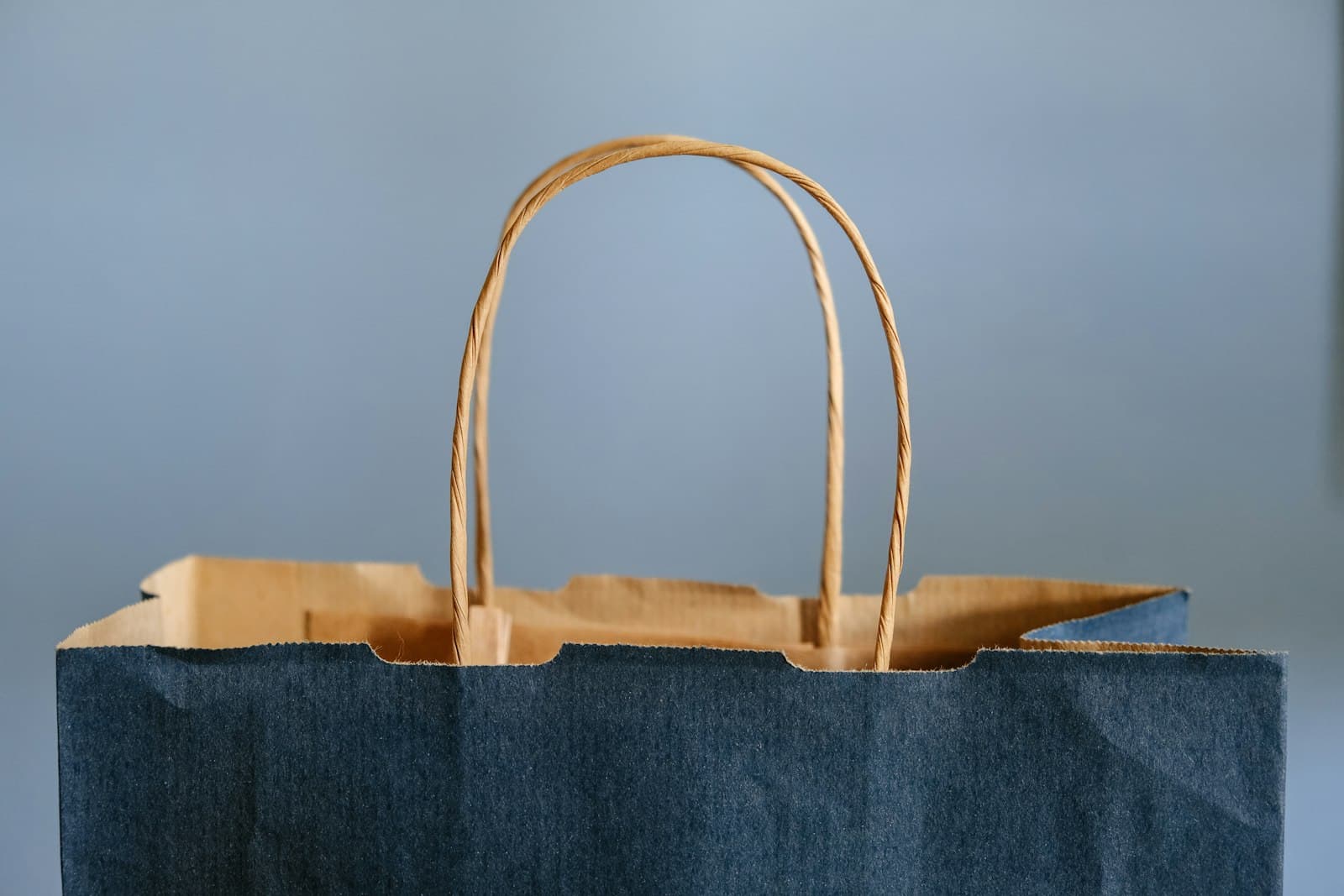 Bolsa de papel azul con asas listas para llevar un pedido, sobre fondo claro